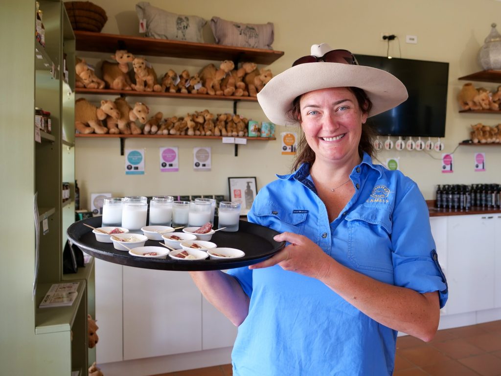 Tour guide holding tray of camel milk and snacks for tasting.