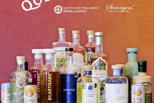 Mulitple bottle of Queensland-produced spirits on a wooden table with a backdrop that reads, Showcasing Queensland.