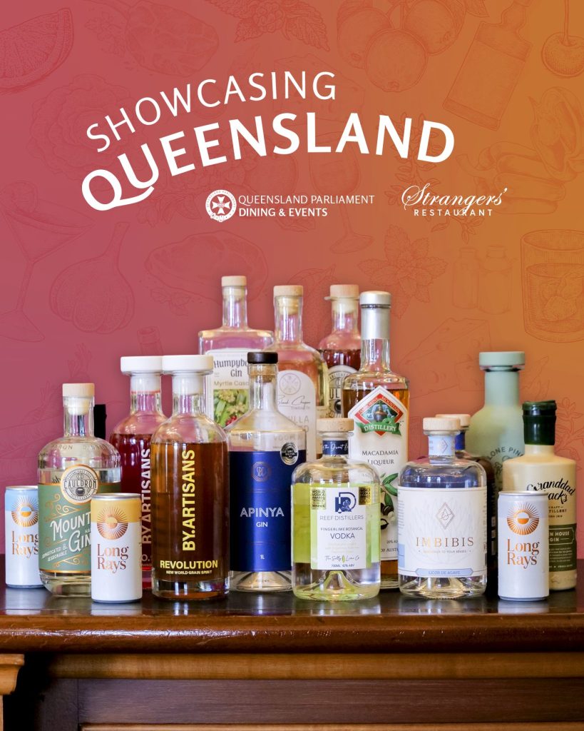 Mulitple bottle of Queensland-produced spirits on a wooden table with a backdrop that reads, Showcasing Queensland.